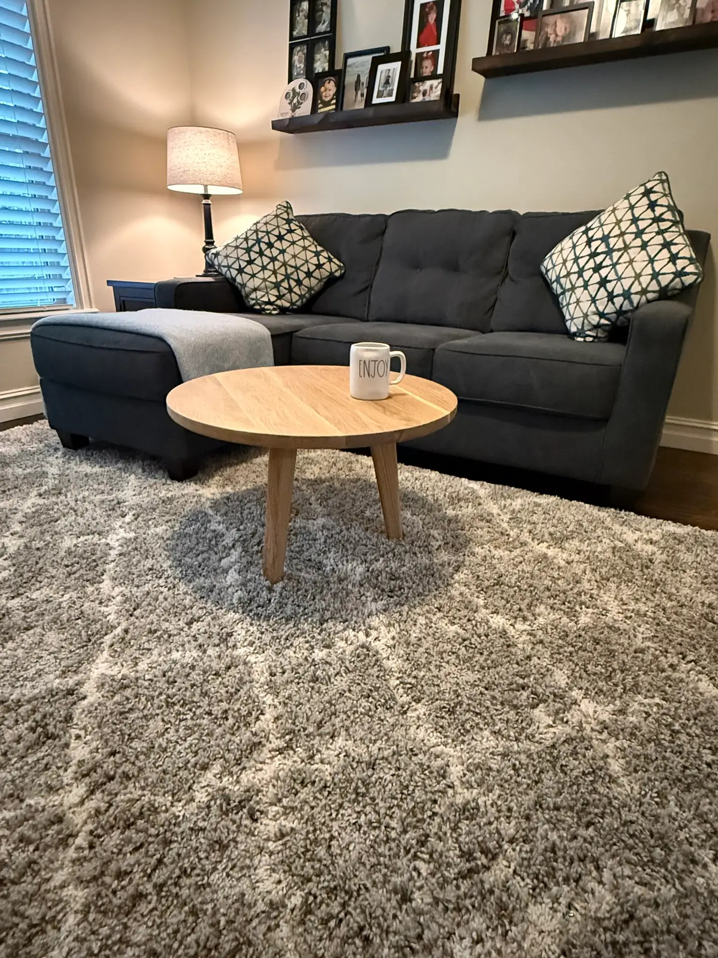 Living room with a round wood coffee table and dark sofa by Westerman Woodworks, Tulsa, Oklahoma